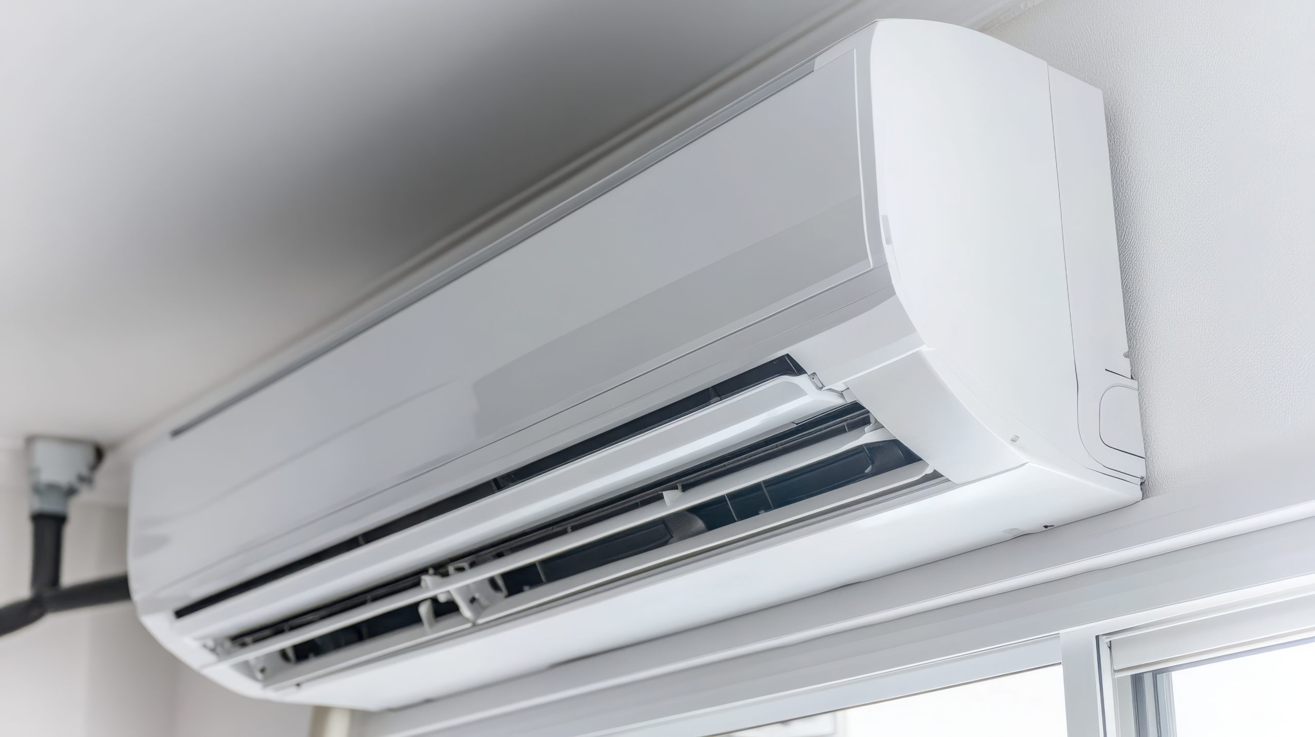 air conditioner indoor unit installed on a wall above the window